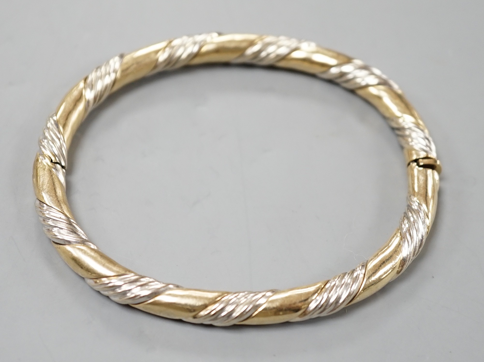A modern two colour 9ct gold hinged bangle, interior diameter 58mm, 18.7 grams.